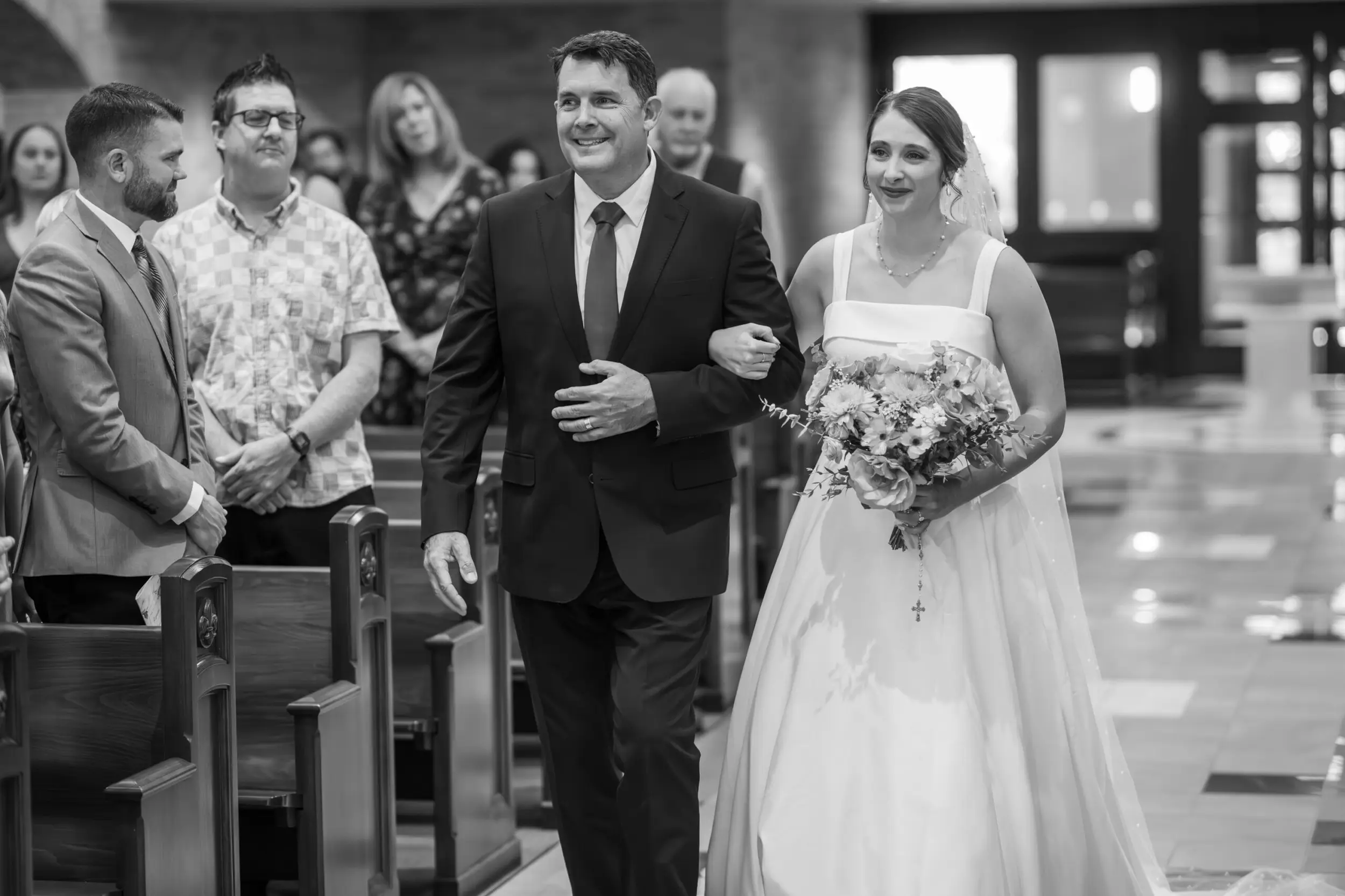 A bride walks down the aisle with her father during her wedding Mass at Our Lady of Lourdes Catholic Church in Denver, Colorado.