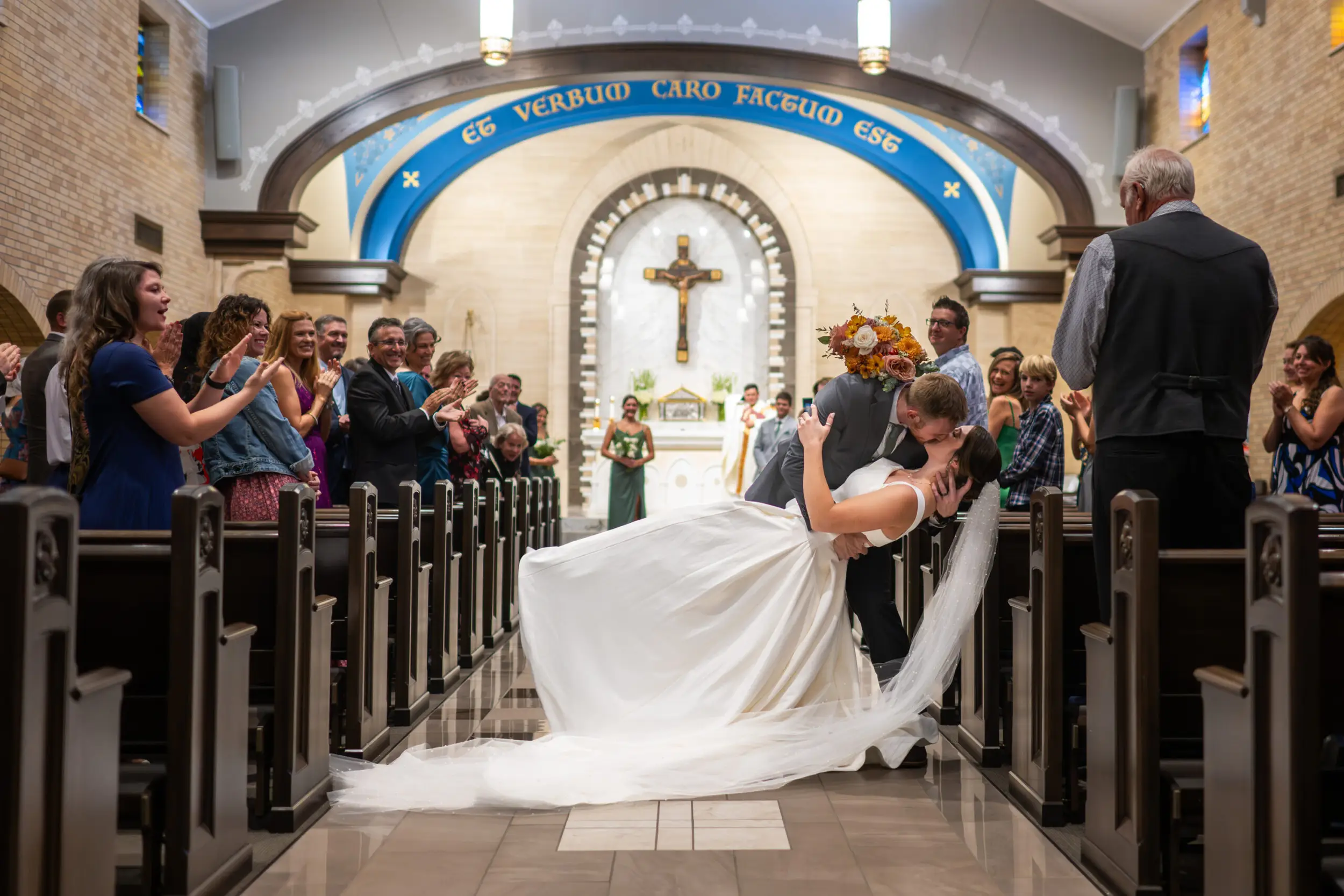 A groom dips his bride and kisses her inside during a wedding at Our Lady of Lourdes Catholic Church in Denver, Colorado.